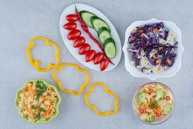 Vegetables salad on white plate with macaroni on marble surface