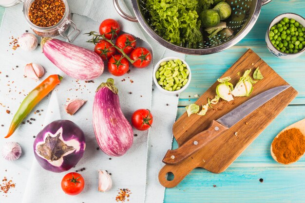 Vegetables and spices with chopping board and knife on wooden table