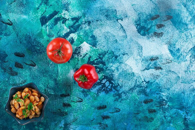 Vegetables with a bowl of baked beans , on the blue table. 