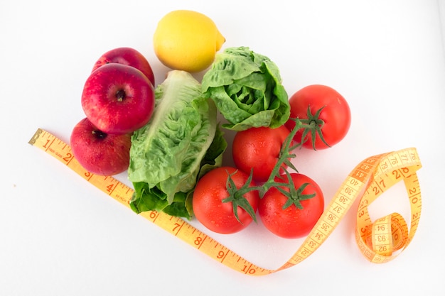 Vegetables with measuring tape on white table