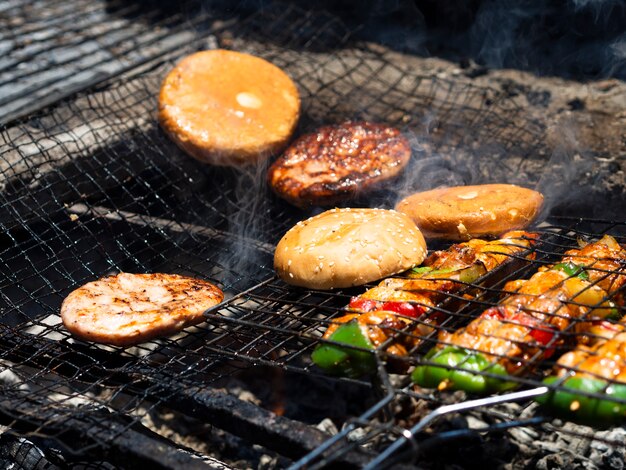 Vegetables with patties and buns grilling on rack