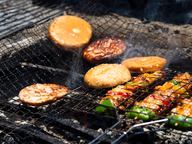 Vegetables with patties and buns grilling on rack