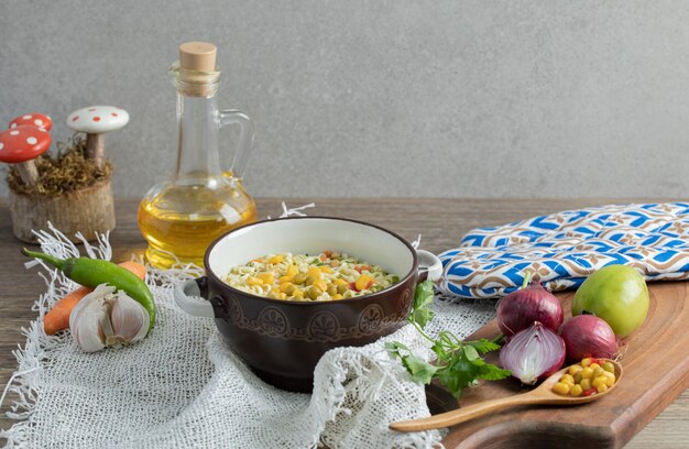 Vegetables on wooden board with bowl of noodles and oil bottle