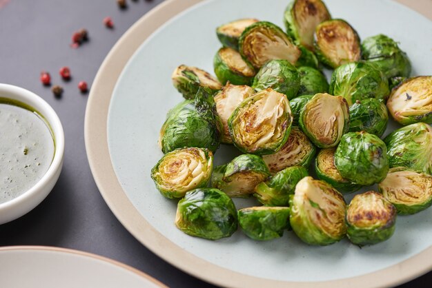 Vegetarian cuisine. Homemade Brussels Sprouts roasted with olive oil in the plate on the table. Copyspace, top view, flatlay.