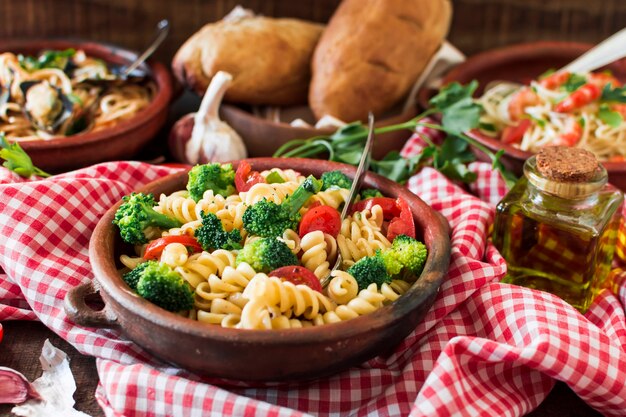 Vegetarian pasta fusilli with tomato and broccoli in the earthenware on tablecloth