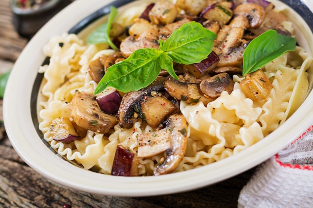 Vegetarian pasta with mushrooms and aubergines, eggplants. Italian food. Vegan meal.