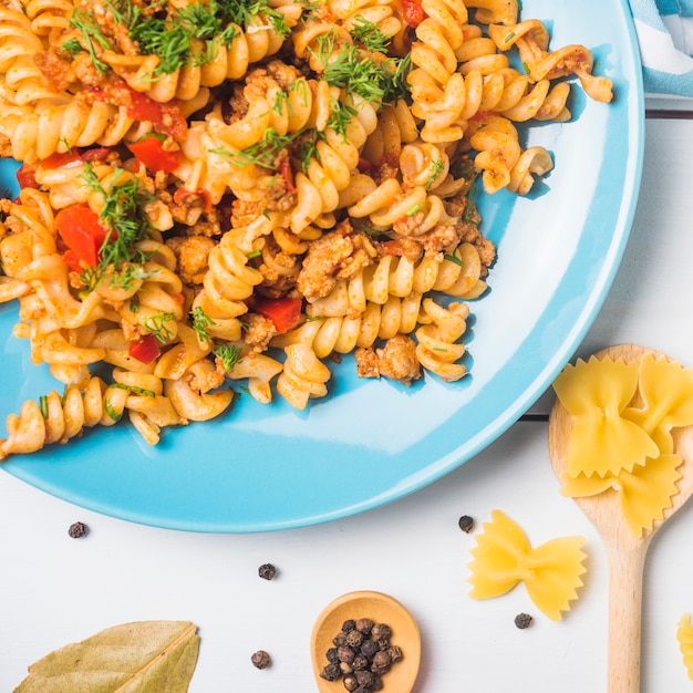 Vegetarian vegetable pasta fusilli on blue plate over white background