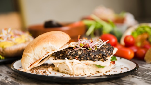 Veggie quinoa burger with sprouts and flax seeds on white plate