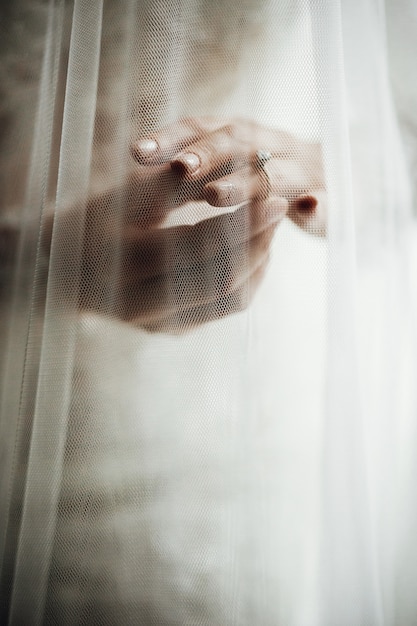 Veil covers bride's hands with wedding rings