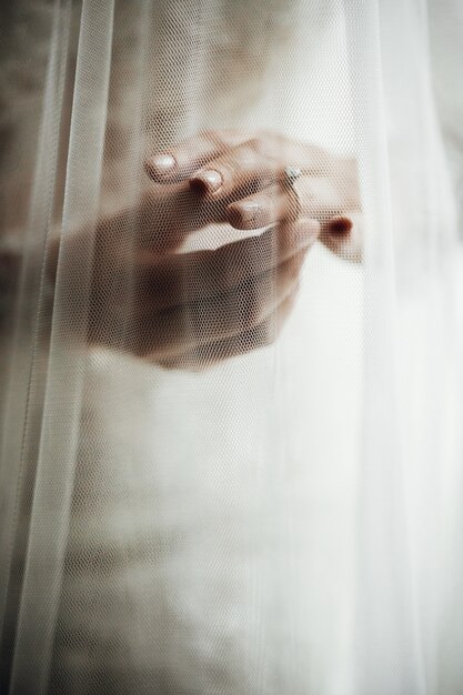 Фата покрывает руки невесты обручальными кольцами