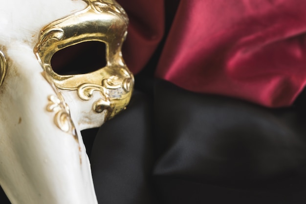 Venetian mask with a long nose on a black fabric close up