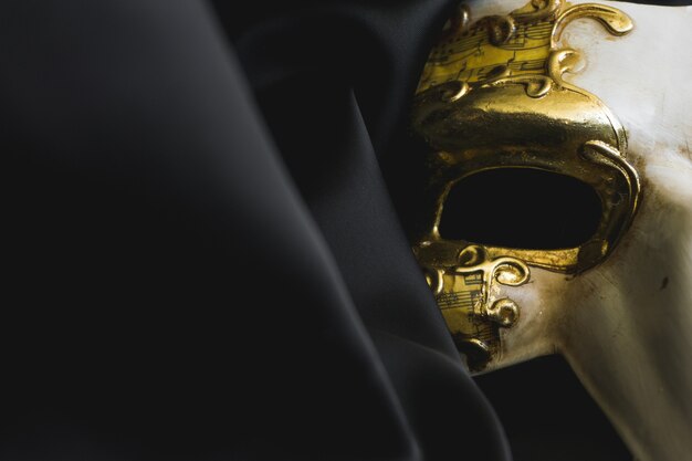venetian mask with a long nose on a black fabric close up