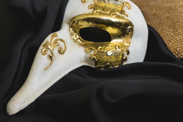 Venetian mask with a long nose on a dark cloth