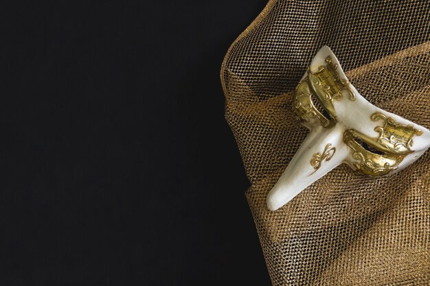 Venetian mask with a long nose on a golden fabric