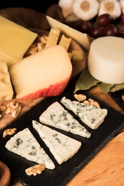 Verity of tasty cheeses and walnut on wooden surface