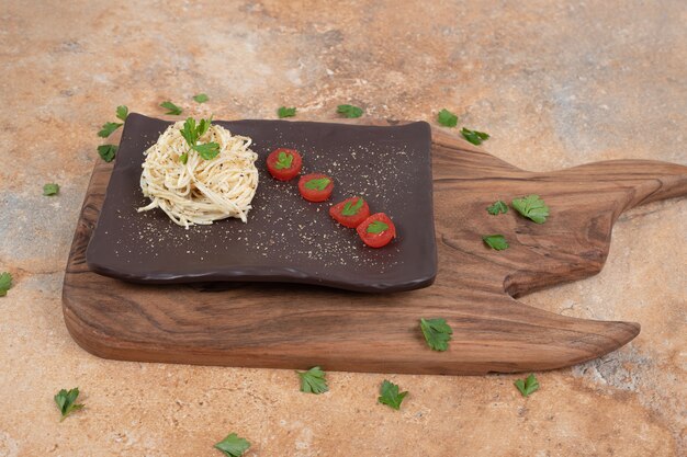 Vermicelli with parsley and tomatoes on black plate. High quality illustration