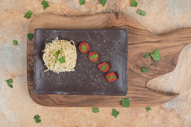 Вермишель со специями и помидорами на черной тарелке. Качественная иллюстрация