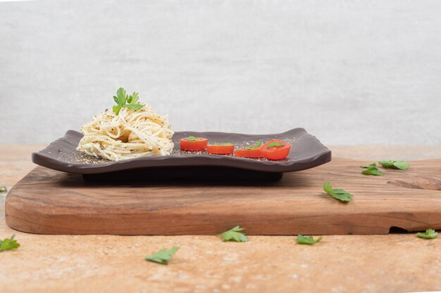 Vermicelli with spices and tomatoes on black plate. 