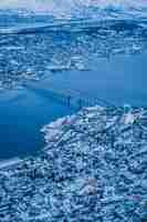 Free photo vertical aerial shot of the beautiful city of tromso covered in snow captured in norway