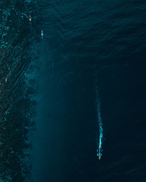 Vertical aerial shot of boats floating on the ocean