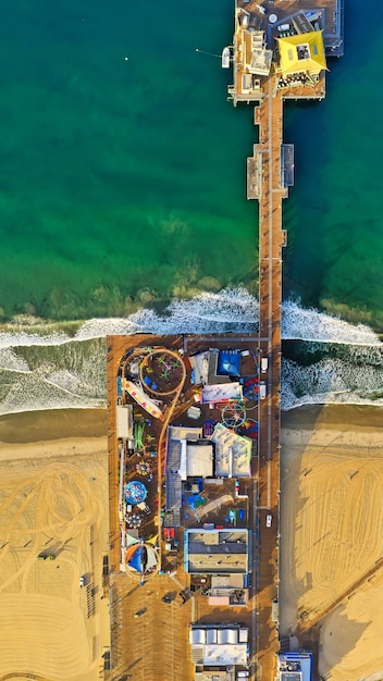 Vertical aerial shot of a park with different kinds of rides at the beach
