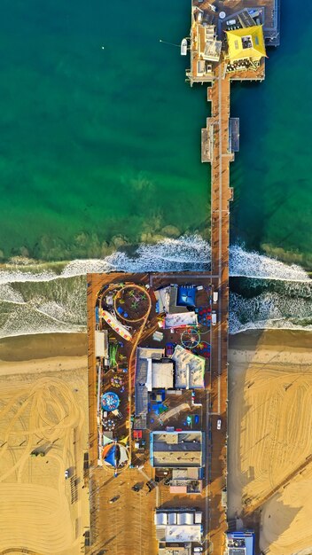 Vertical aerial shot of a park with different kinds of rides at the beach