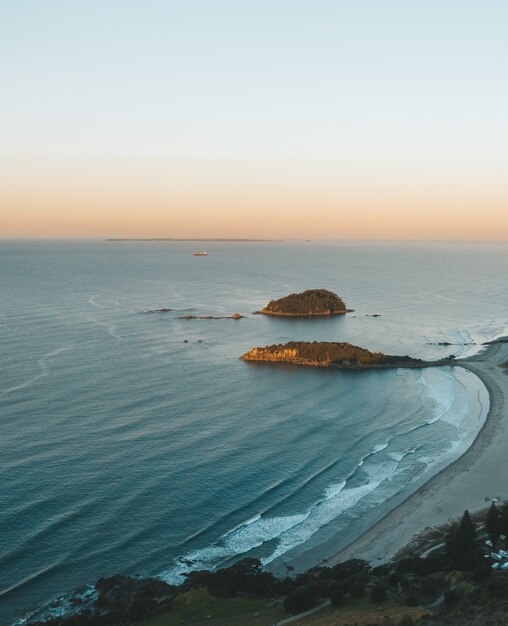 Vertical aerial shot of a seashore with rocks and a clear sky