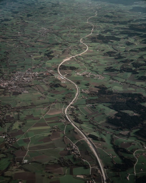 Vertical bird-eye view of an endless road and green fields