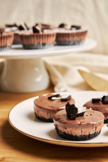 Vertical closeup of creamy chocolate cheesecake muffins on plates under the lights