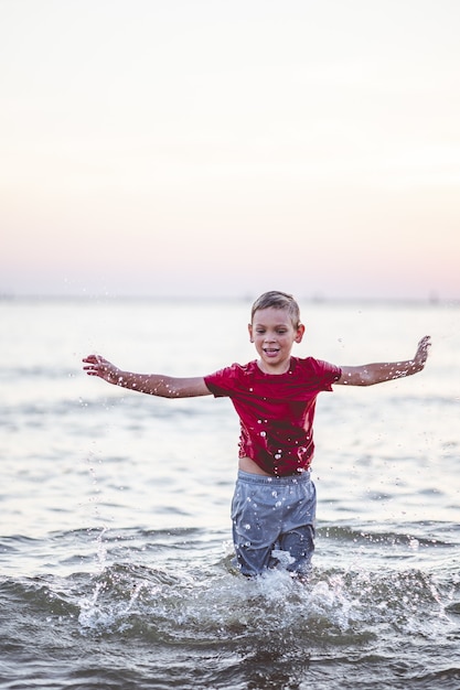 Free photo vertical closeup focus portrait of a young boy standing in the sea