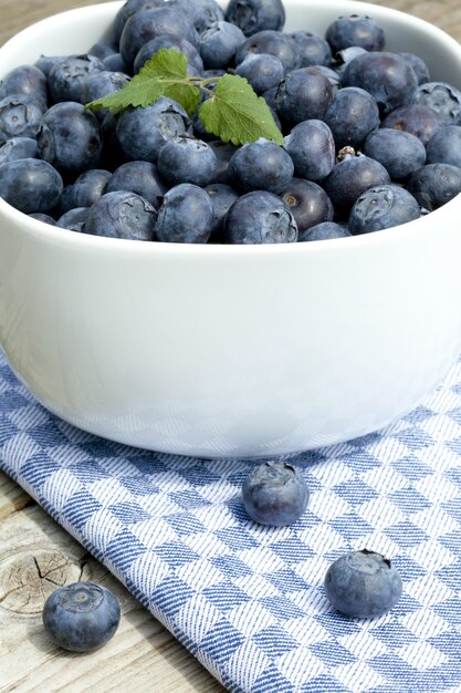 Vertical closeup of fresh blueberries in a white bowl