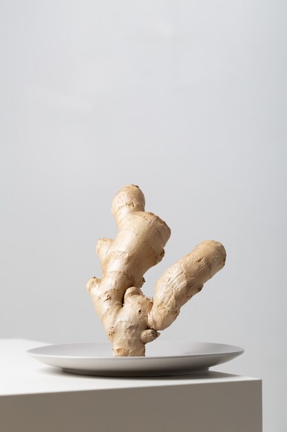 Vertical closeup of ginger on a plate on the table under the lights against a white background