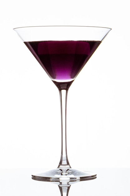 Vertical closeup of a glass of purple cocktail isolated on a white background