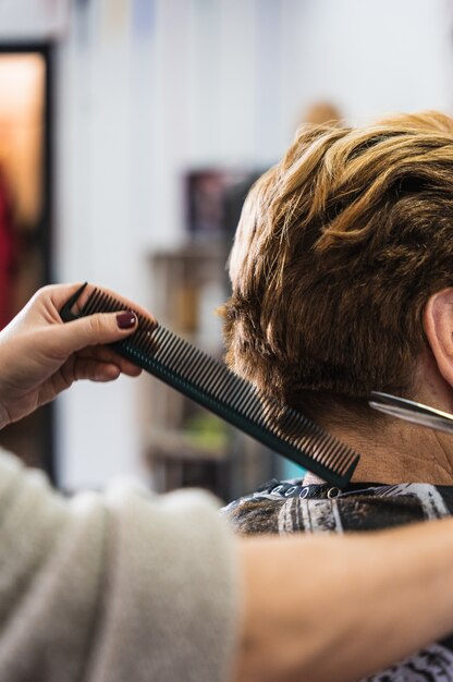 Vertical closeup of a hairdresser cutting a woman's short hair in a beauty salon