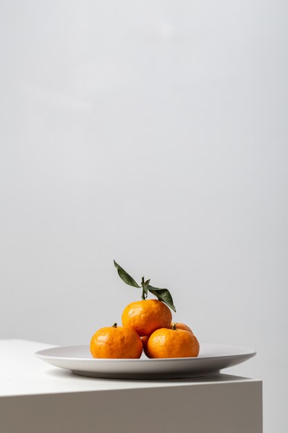 흰색 배경 조명 아래 테이블에 접시에 mandarines의 수직 근접 촬영
