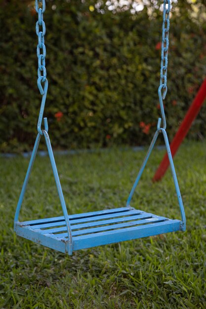 Vertical closeup of an old blue swing in a garden surrounded by greenery in Mexico