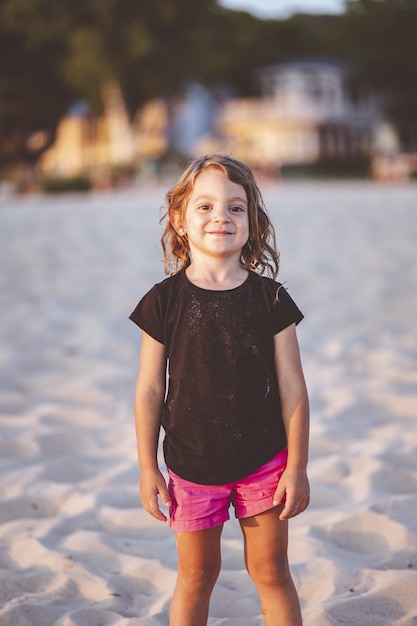 Free photo vertical closeup portrait of an adorable young girl standing at the beach