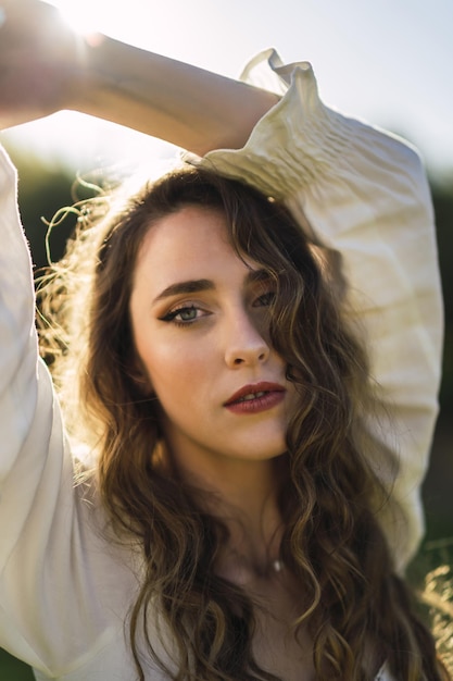 Foto gratuita colpo verticale del primo piano di una bella donna caucasica dalla spagna nella parte superiore bianca in tempo soleggiato