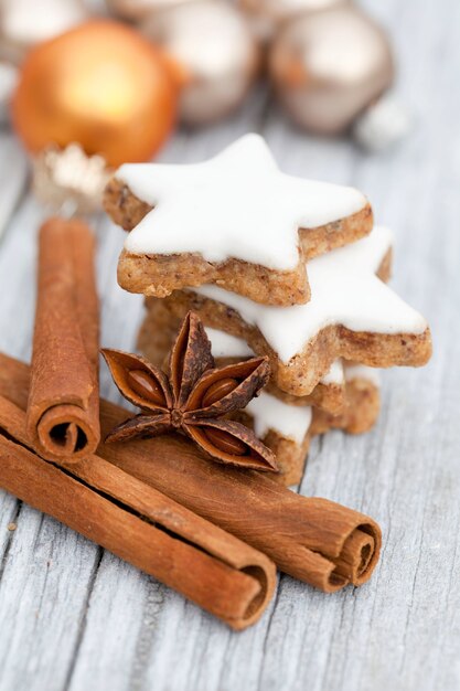 Vertical closeup shot of cinnamon sticks and a stack of star-shaped gingerbread cookies on a table