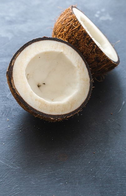 Vertical closeup shot of cut coconuts on a grey surface