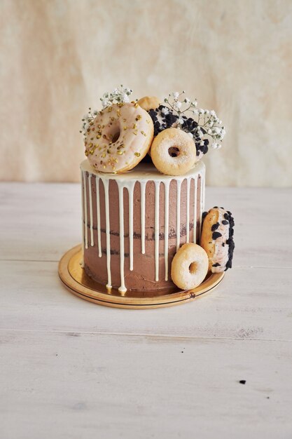 Vertical closeup shot of delicious Donut choco Birthday cake with donuts on top and white drip