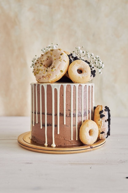 Vertical closeup shot of delicious Donut choco Birthday cake with donuts on top and white drip