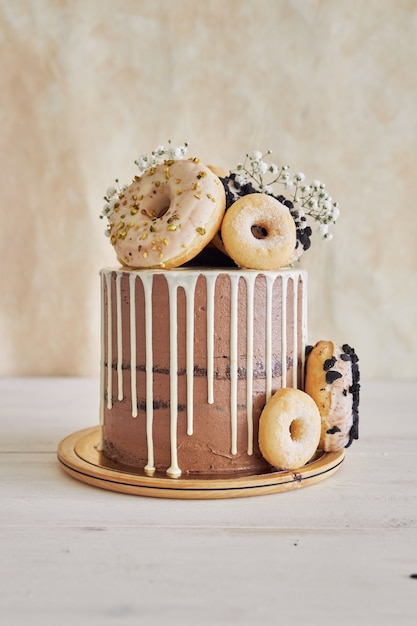 상단 및 흰색 물방울에 도넛이 있는 맛있는 도넛 초코 생일 케이크의 수직 근접 촬영