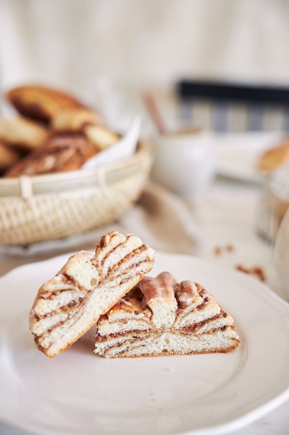 Vertical closeup shot of delicious Nut snails with coffee Cappuccino on the white wood table