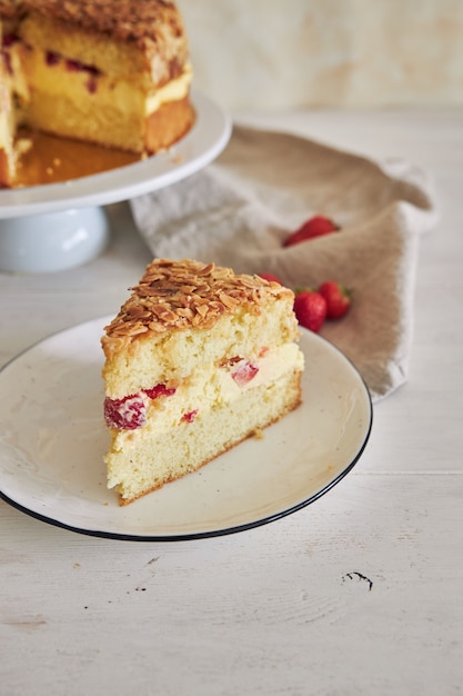 Primo piano verticale della deliziosa torta alla crema di vaniglia con fragole all'interno su un tavolo bianco