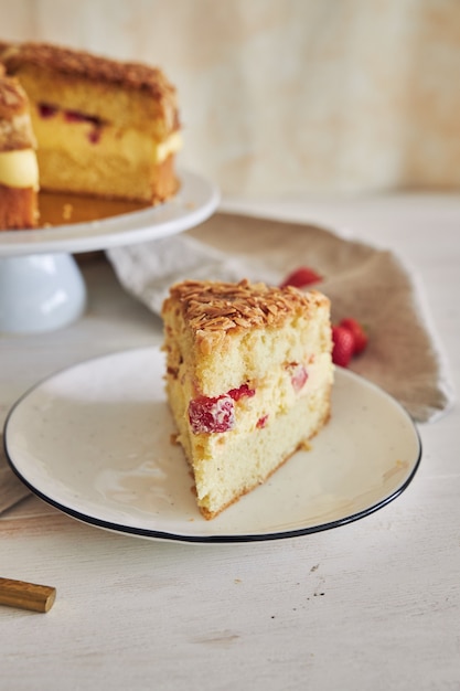 하얀 테이블에 딸기가 들어 있는 맛있는 바닐라 크림 케이크의 수직 클로즈업 샷