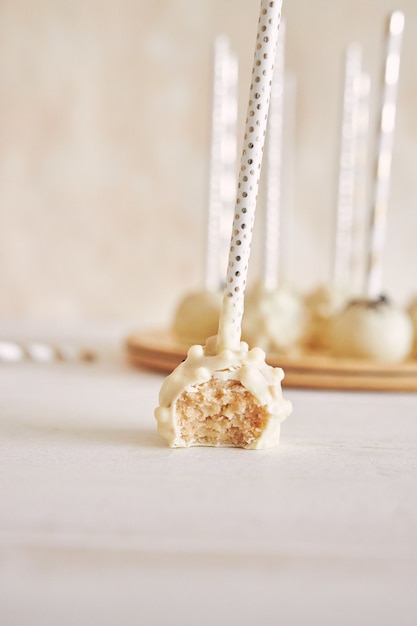 Free photo vertical closeup shot of delicious white cake pops on a white table