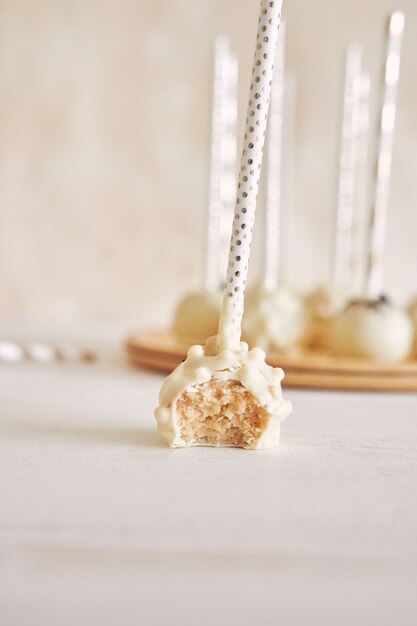 Vertical closeup shot of delicious white Cake pops on a white table