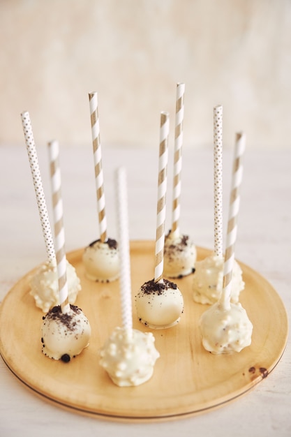 Vertical closeup shot of delicious white Cake pops on a white and wooden table