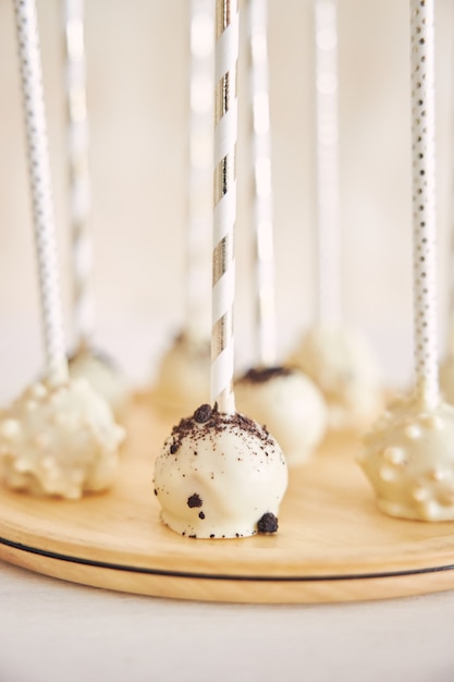 Vertical closeup shot of delicious white Cake pops on a white and wooden table